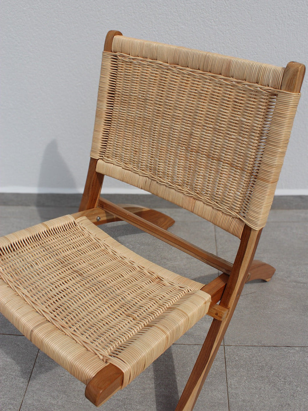 AYOMI Bali katlanır sandalye, doğal tik ağacı iskelet ve el örgüsü rattan oturma yüzeyine sahip şık bahçe mobilyası.