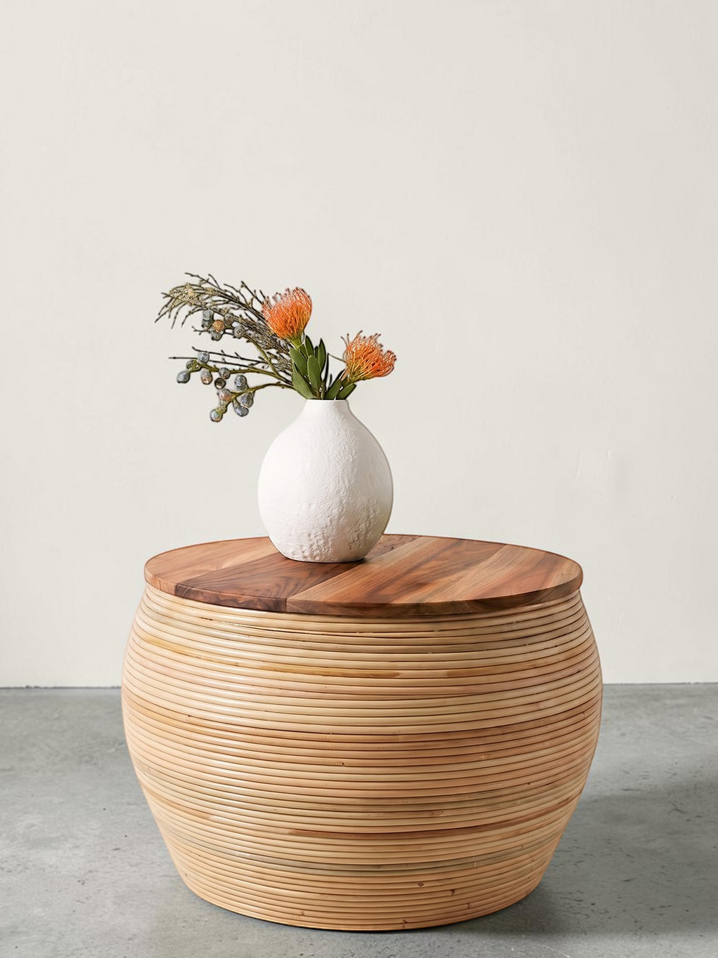 AYOMI handmade round coffee table with a natural bamboo base and a smooth teak wood top, styled with a white vase.