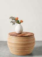 AYOMI handmade round coffee table with a natural bamboo base and a smooth teak wood top, styled with a white vase.