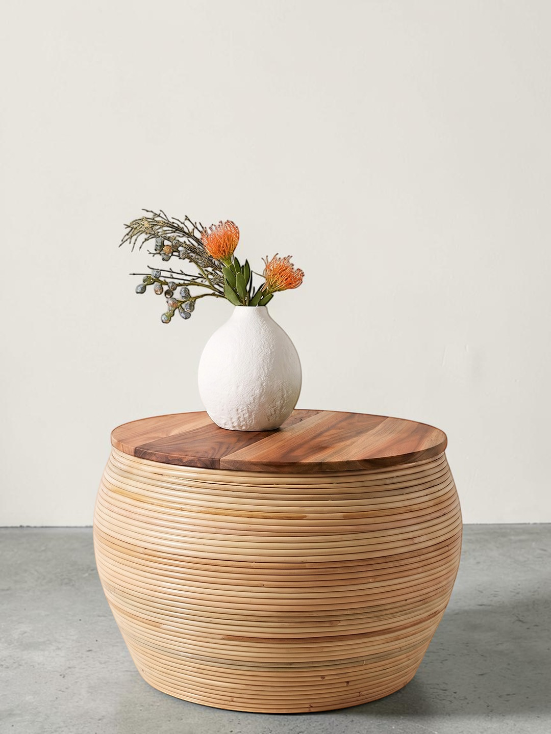AYOMI handmade round coffee table with a natural bamboo base and a smooth teak wood top, styled with a white vase.