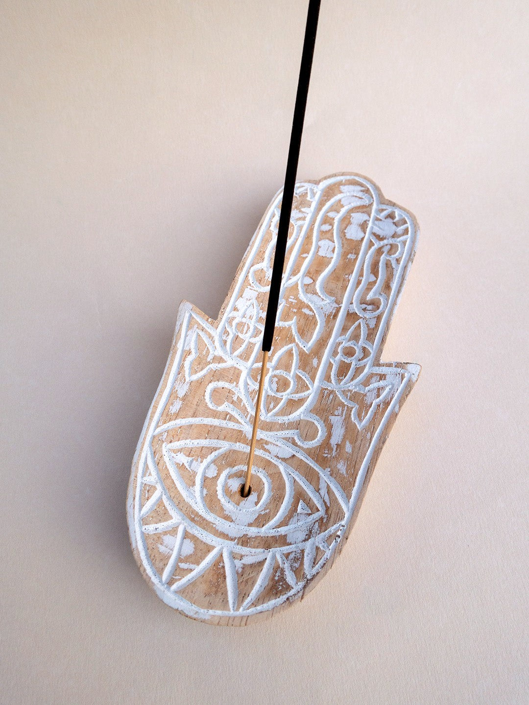 19 cm ahşap Hamsa tütsülüğün göz motifindeki deliğe yerleştirilmiş tütsü çubuğu yakından görülmektedir