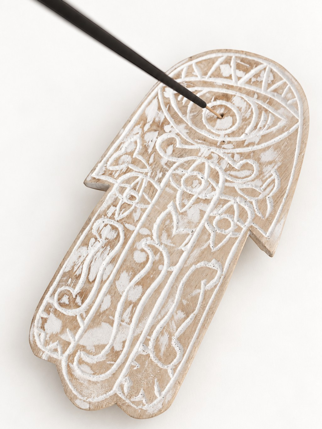 AYOMI hand-carved balsa wood Hamsa incense holder with white painted eye and floral details on a white background.