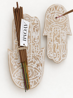 AYOMI hand-carved wooden Hamsa incense holder with eye detail and incense sticks on a white background