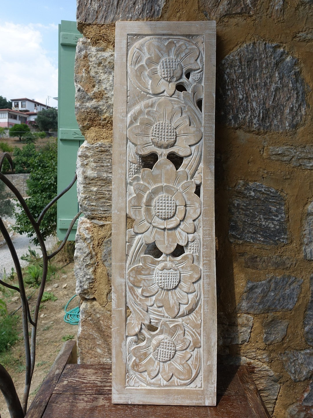 AYOMI Sakura ahşap oyma beyaz duvar dekoru, çiçek motifli 100x27 cm. Taş duvarlı bir evde duvarda.
